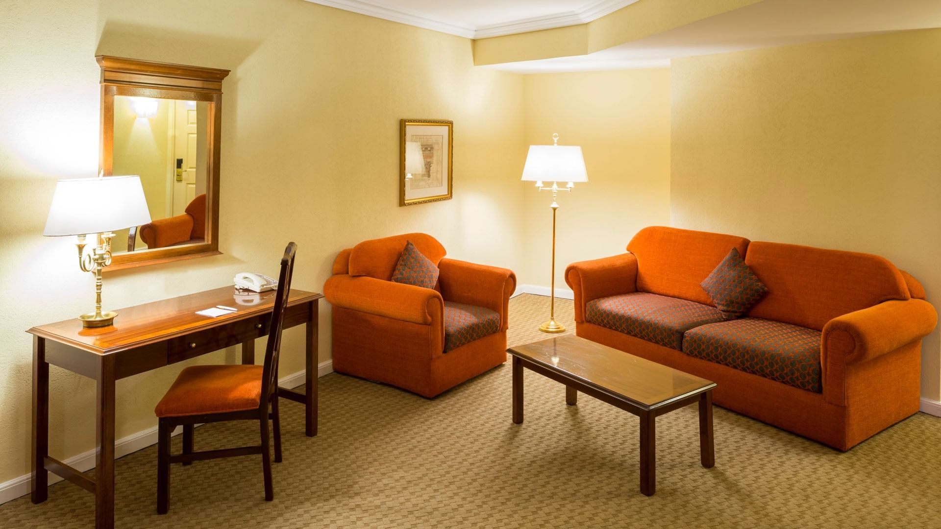 Sala de estar de Junior Suite King con sofá naranja, escritorio y lámpara en Camino Real Puebla Angelópolis