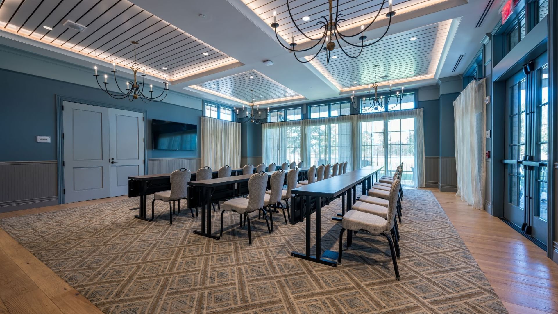 Club Room with long conference table, upholstered chairs, chandeliers, and large windows at Camp Creek Inn in Inlet Beach.