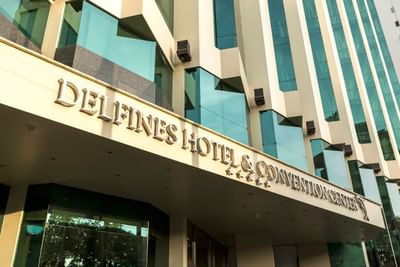 Facade of Delfines Hotel & Convention Center featuring modern architecture and a large sign