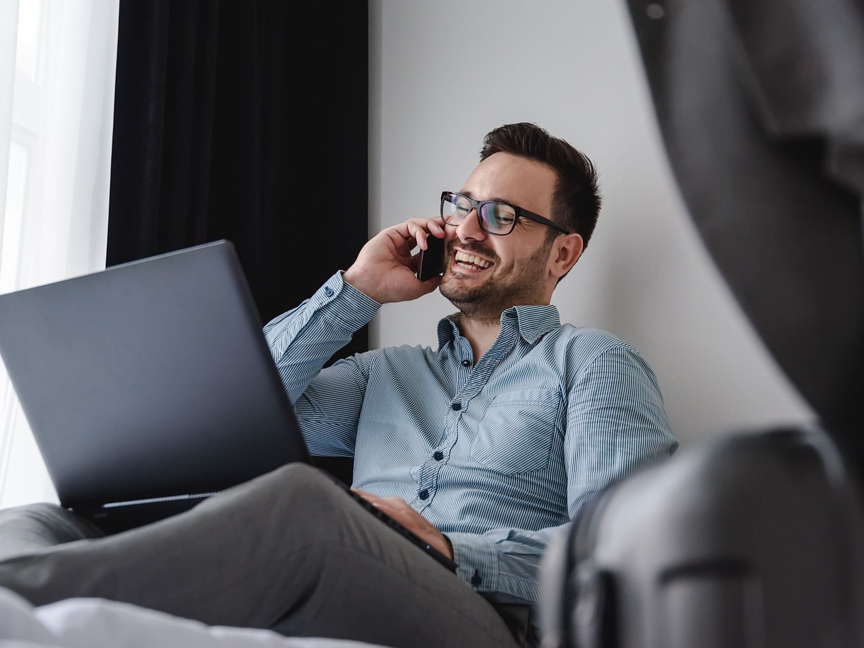 Man on a laptop while answering the mobile at Originals Hotels