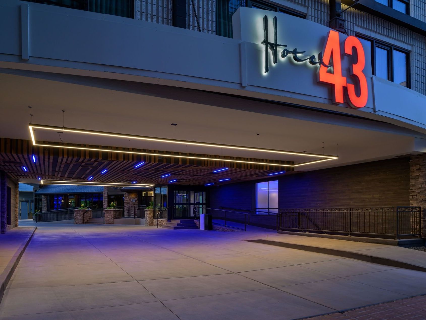 The entrance of Hotel 43 Boise at dusk with modern blue and yellow lighting highlighting the sleek design
