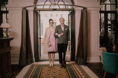 Woman dressed in pink and a man in a suit stand confidently at Hotel Motto Vienna’s elegant entrance