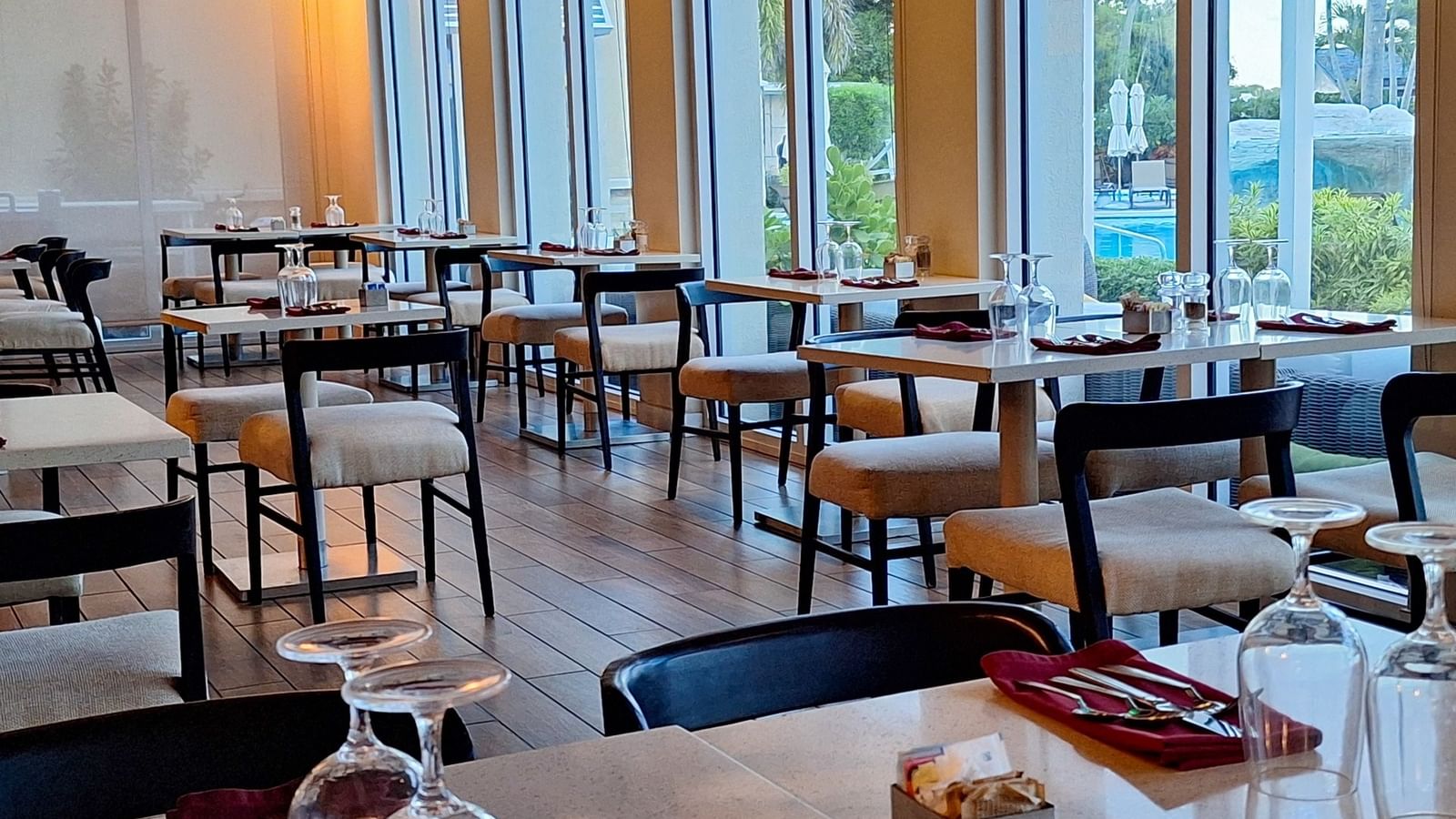 Verandah restaurant interior with Tables & glasses by padded chairs under soft light at Warwick Paradise Island Bahamas