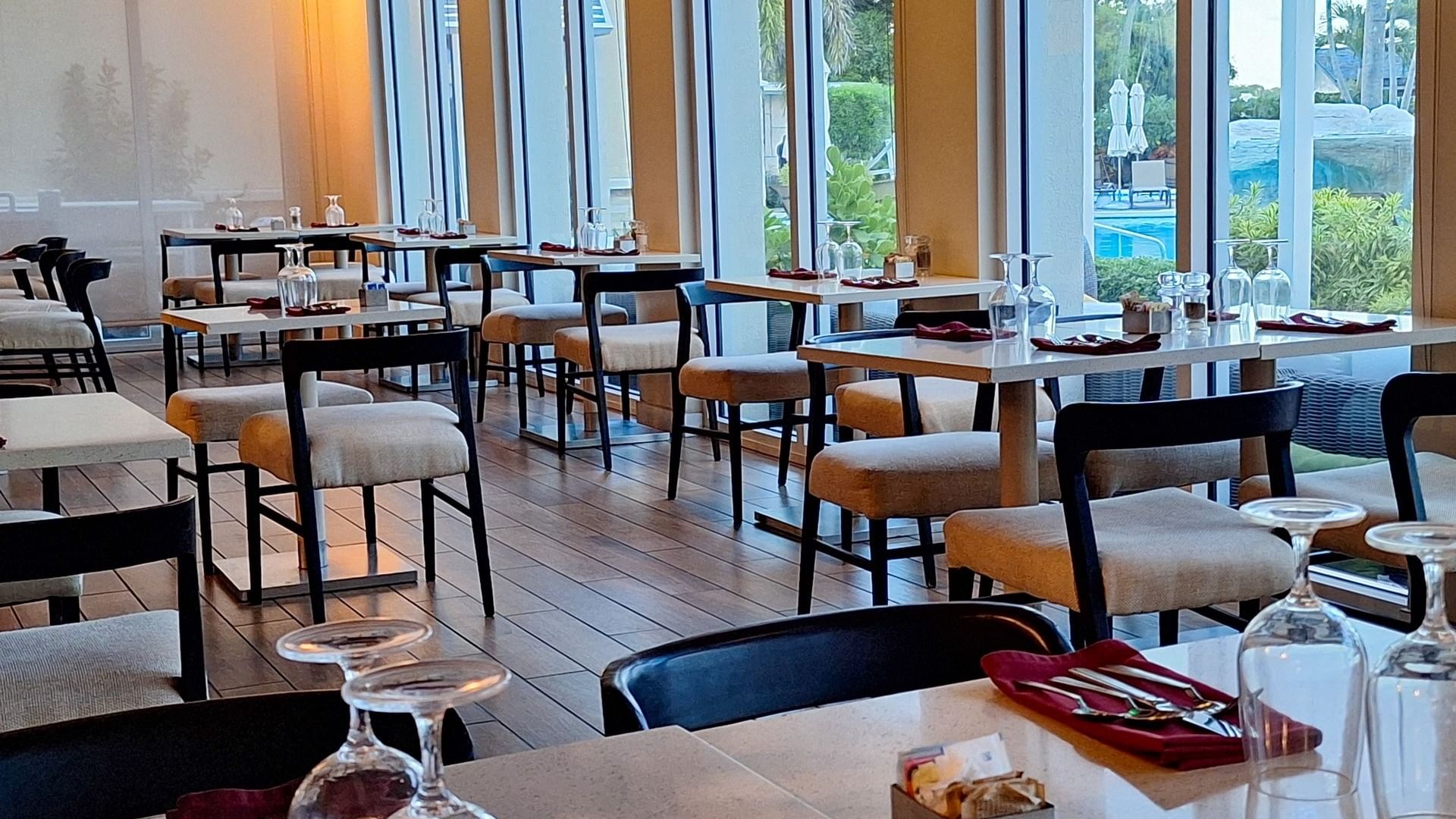 Verandah restaurant interior with Tables & glasses by padded chairs under soft light at Warwick Paradise Island Bahamas