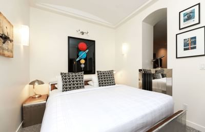 A spacious, pristine first-class suite with a comfortable bed and elegant planet-themed artwork.