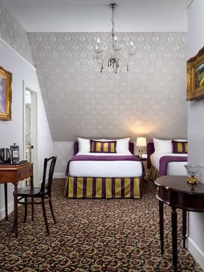 Two double beds and a chandelier in Amelia Jane Room at Pendray Inn & Tea House