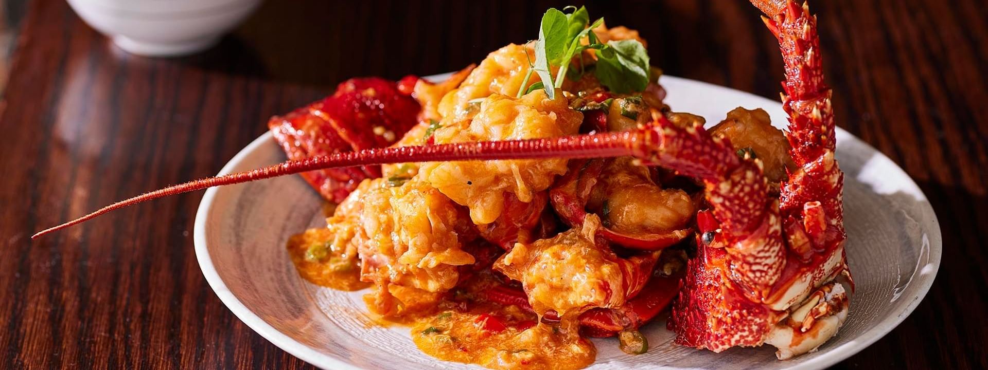 Lobster dish with a rich sauce on a plate, garnished with herbs served in Silks Restaurant at Crown Hotel Melbourne