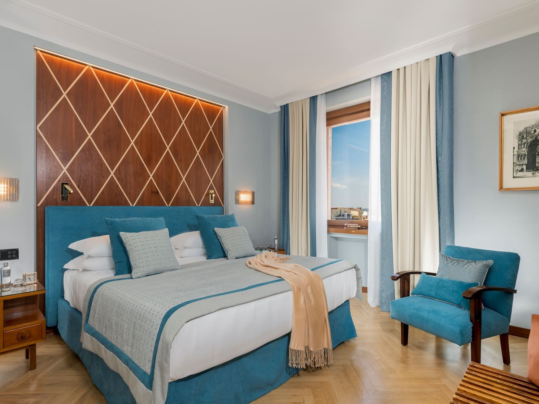 Comfy bed, blue pillows & chair in Premium Deluxe Room at Bettoja Hotel Mediterraneo