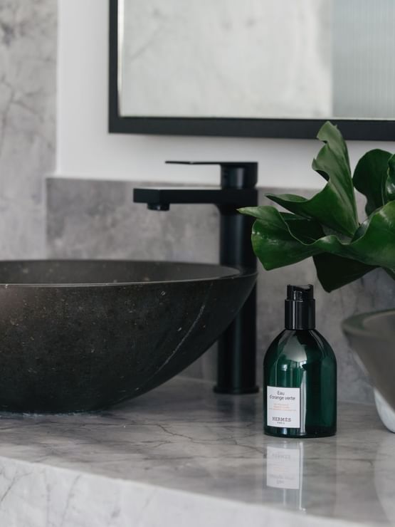 Elysium Suite at Elysium Manly showcases a black vessel sink by a matching faucet, with a dark green bottle
