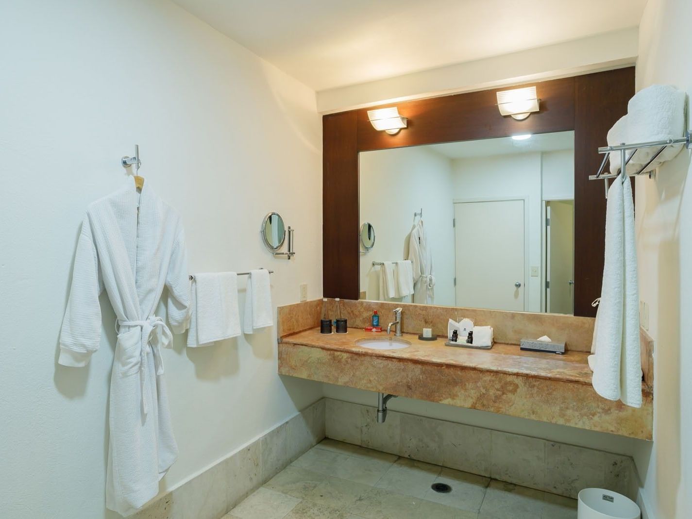 King Junior Suite bathroom mirror and vanity featuring plush white robes and professional lighting at Camino Real Pachuca