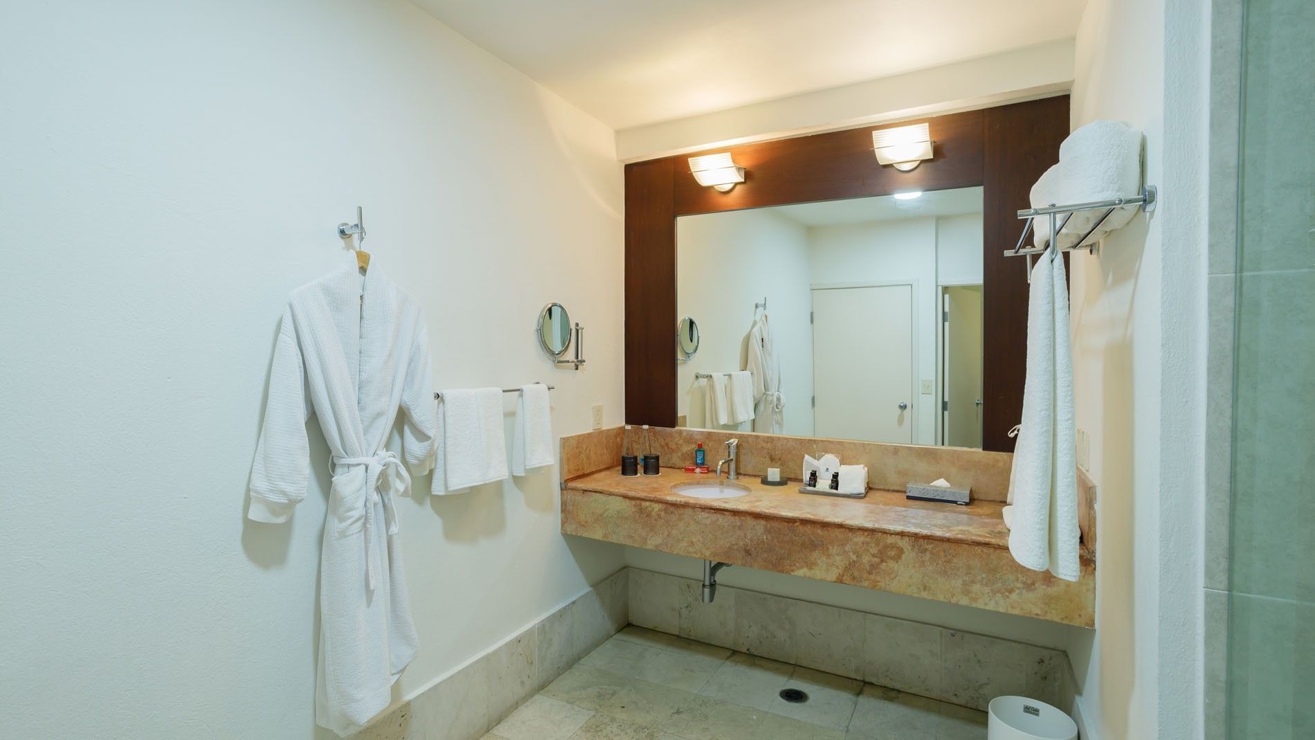 King Junior Suite bathroom mirror and vanity featuring plush white robes and professional lighting at Camino Real Pachuca