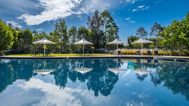 Outdoor pool with sun loungers and white parasols at Mercure Kooindah Waters