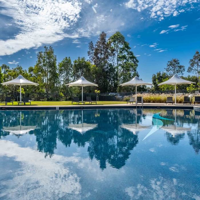 Outdoor pool with sun loungers and white parasols at Mercure Kooindah Waters