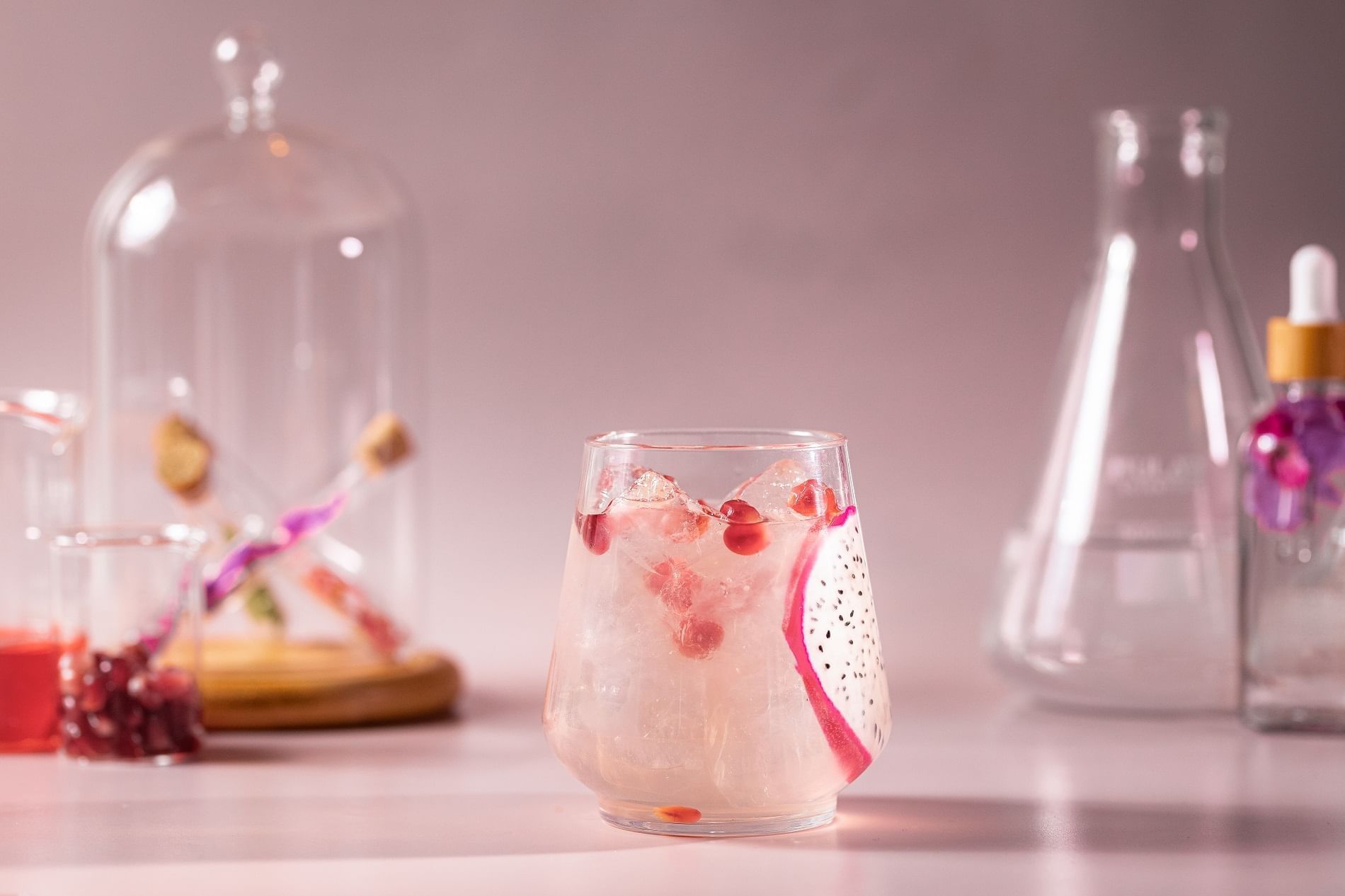 Close-up of a stunning, light pink cocktail with dragon fruit and pomegranate seeds in a glass, served at The Londoner Hotel