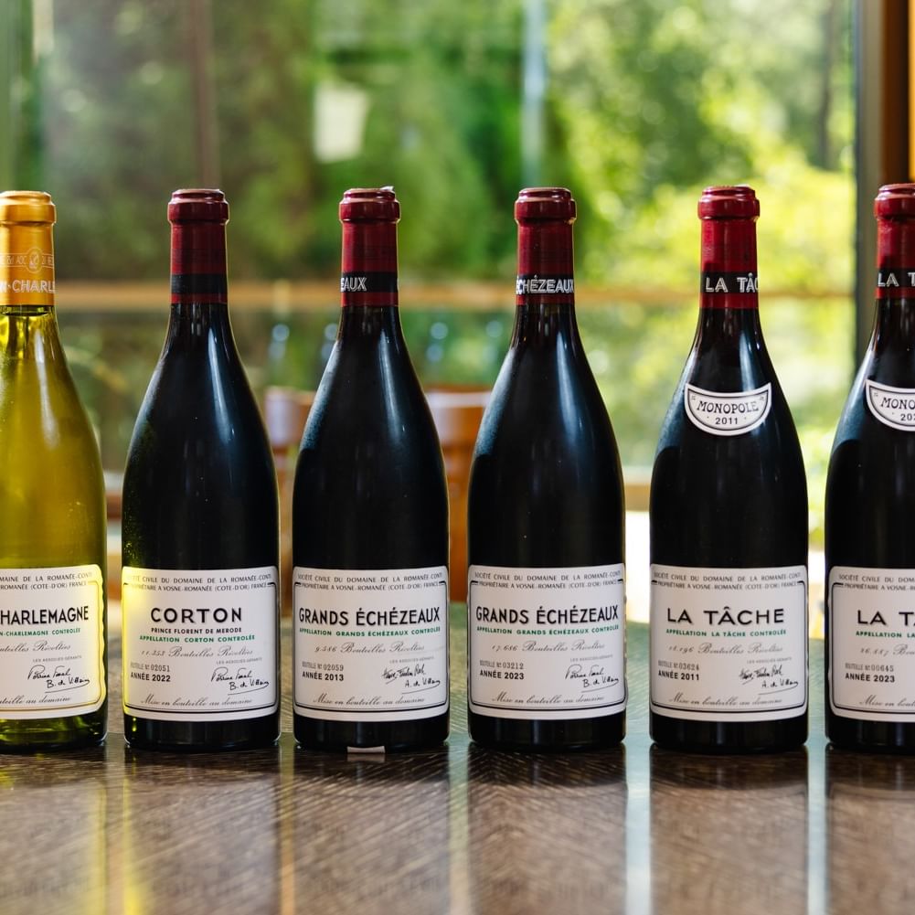 Six premium French wine bottles displayed on a table with yellow patterned cushions for Herons × DRC event.