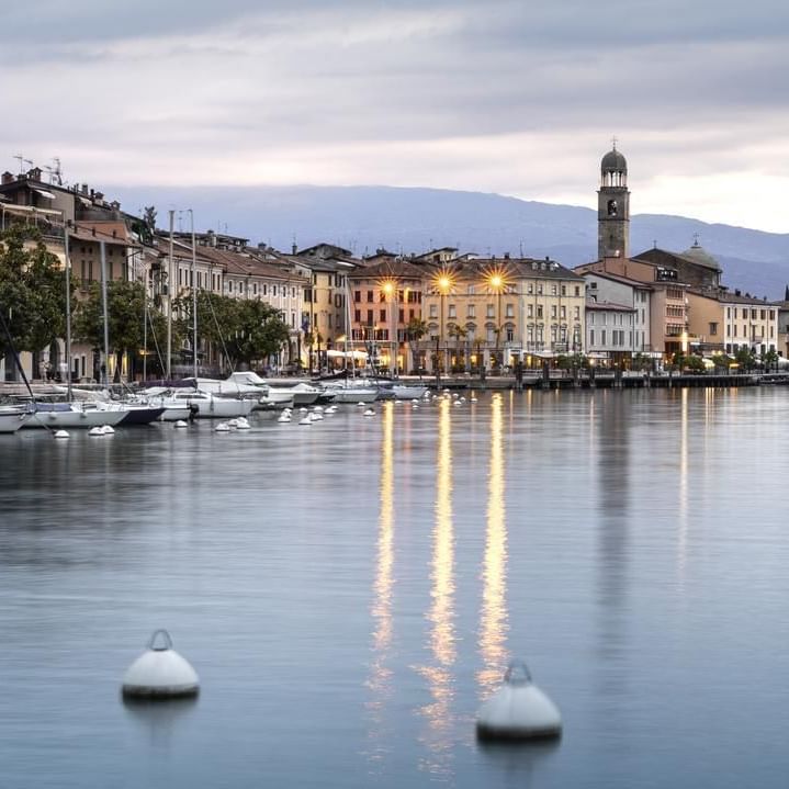 Vista panoramica di un lago con molte barche ormeggiate e edifici sulla riva.