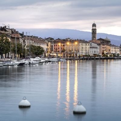 Hafenansicht mit mehreren Segelbooten, Gebäuden am Ufer und einer Kirche im Hintergrund.