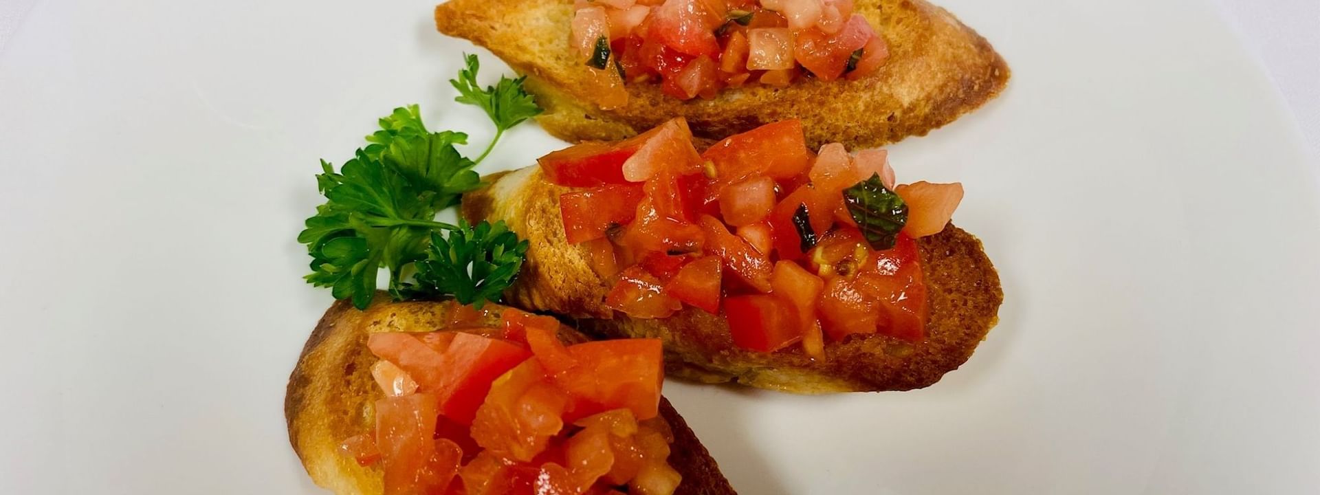 Tomato bruschetta with a parsley garnish surrounding toasted bread on a plate in Abbiocco at Warwick Paradise Island Bahamas
