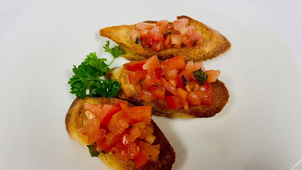 Tomato bruschetta with a parsley garnish surrounding toasted bread on a plate in Abbiocco at Warwick Paradise Island Bahamas