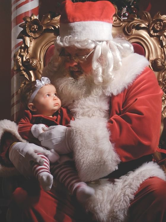 Santa Claus holding a baby near Marv Herzog Hotel