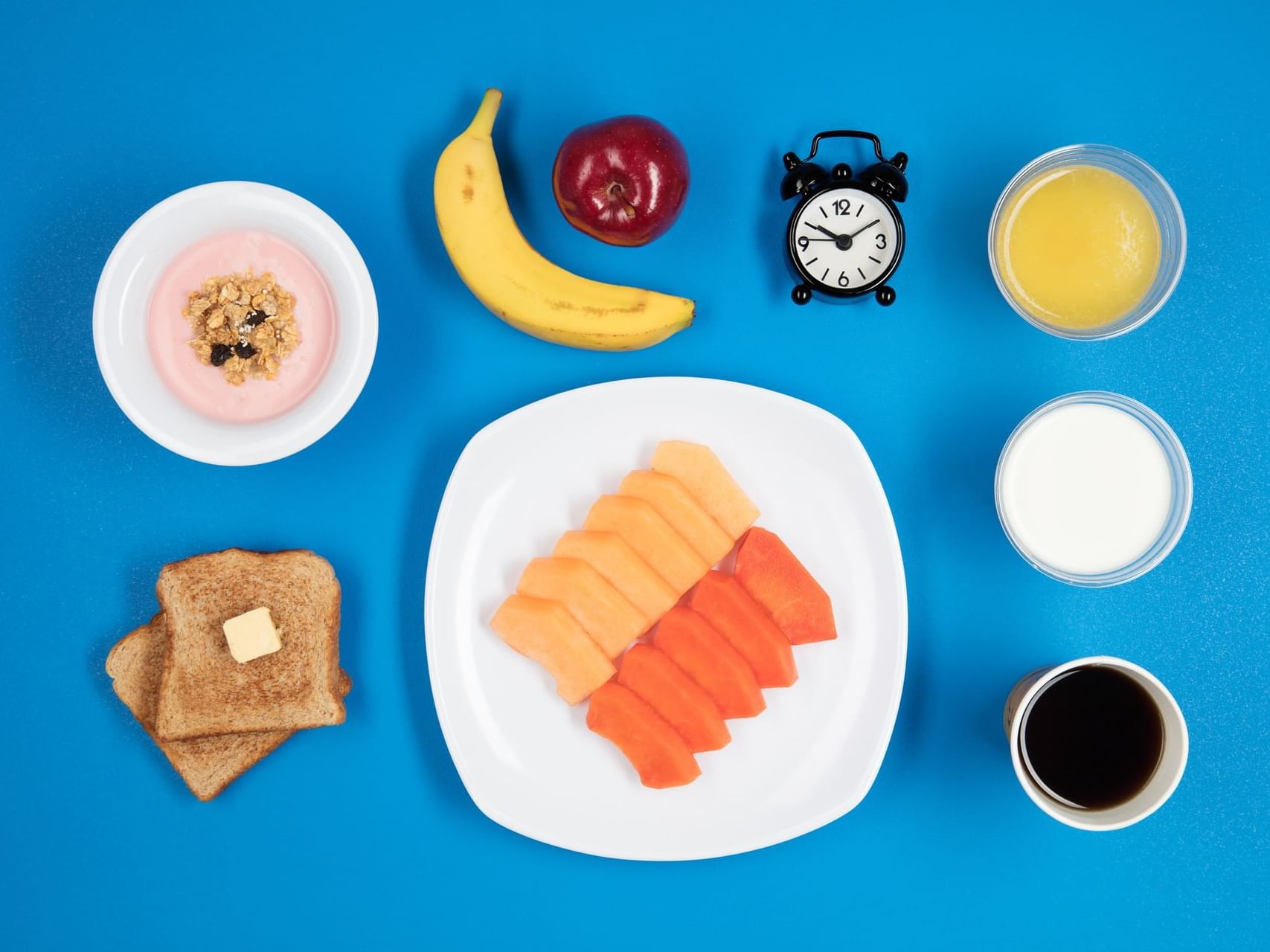 Close-up of fruits and bread arranged with sauces and a clock on blue background at One Hotels