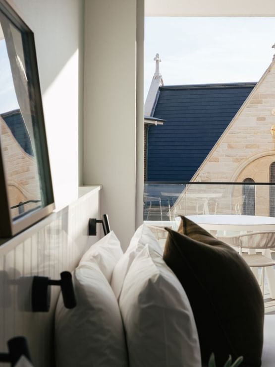 Village Terrace Twin at Elysium Manly with white pillows by a balcony, looking at a stone church building