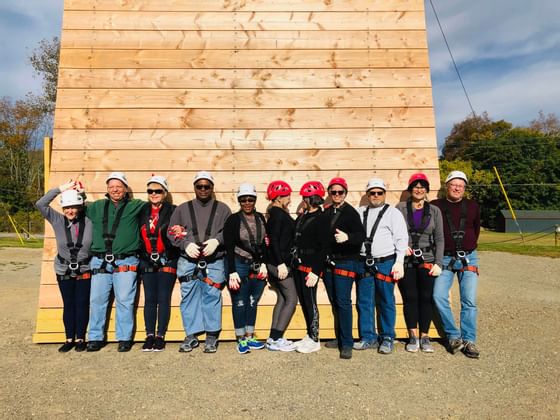 People posing by a climbing wall near Honor’s Haven Retreat