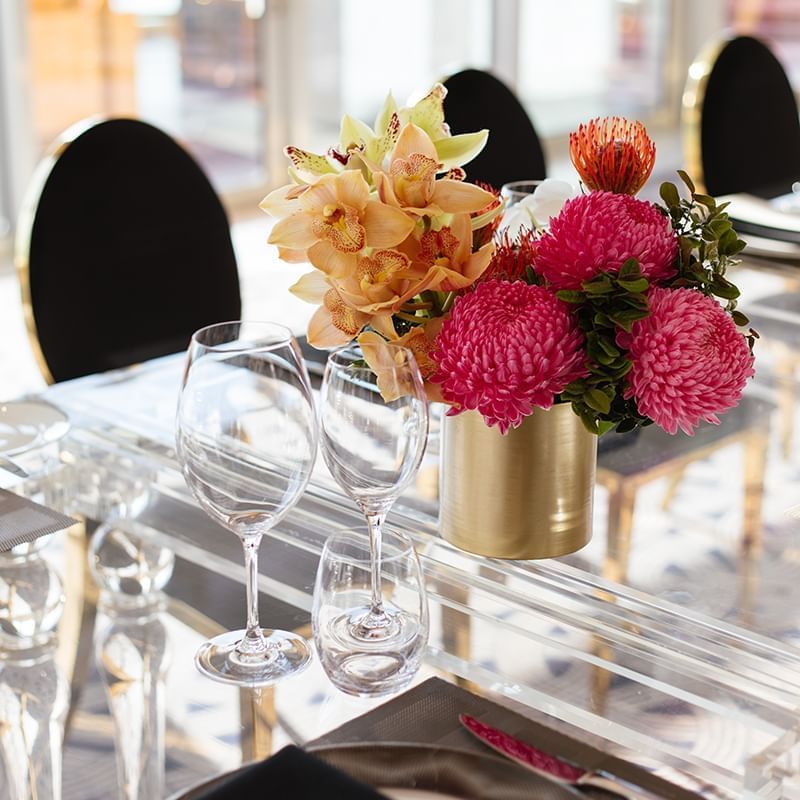 Elegant dining table setting with floral centerpiece, crystal stemware and chairs at Crown hotels Perth