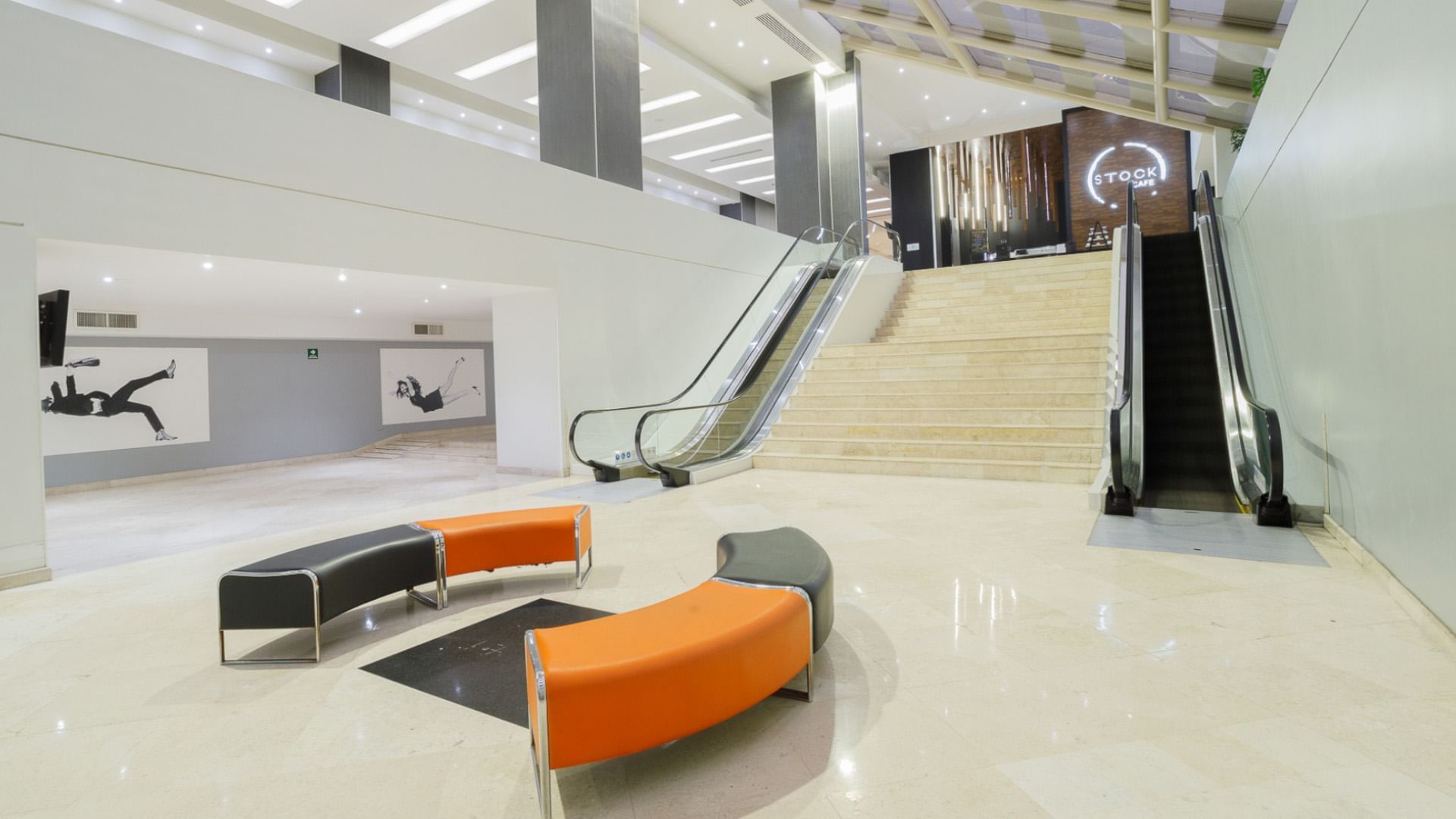 Spacious multi-level lobby with marble stairs, escalators, and modern curved seating at the Real Inn Tijuana