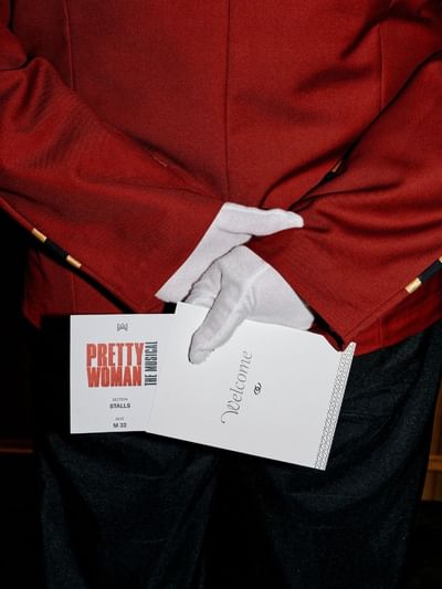 Bellboy holding a ticket for Pretty Woman: The Musical Package.
