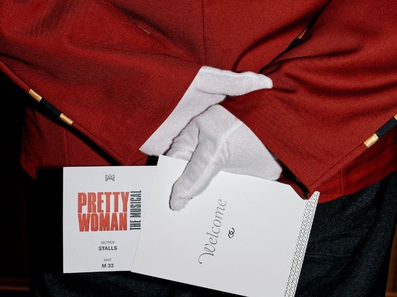 Bellboy holding a ticket for Pretty Woman: The Musical Package.