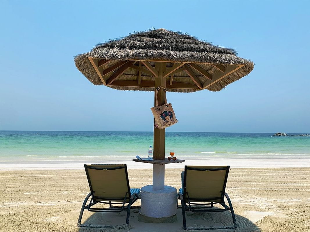A relaxing area with 2 sunbeds on the beach at Ajman Hotel