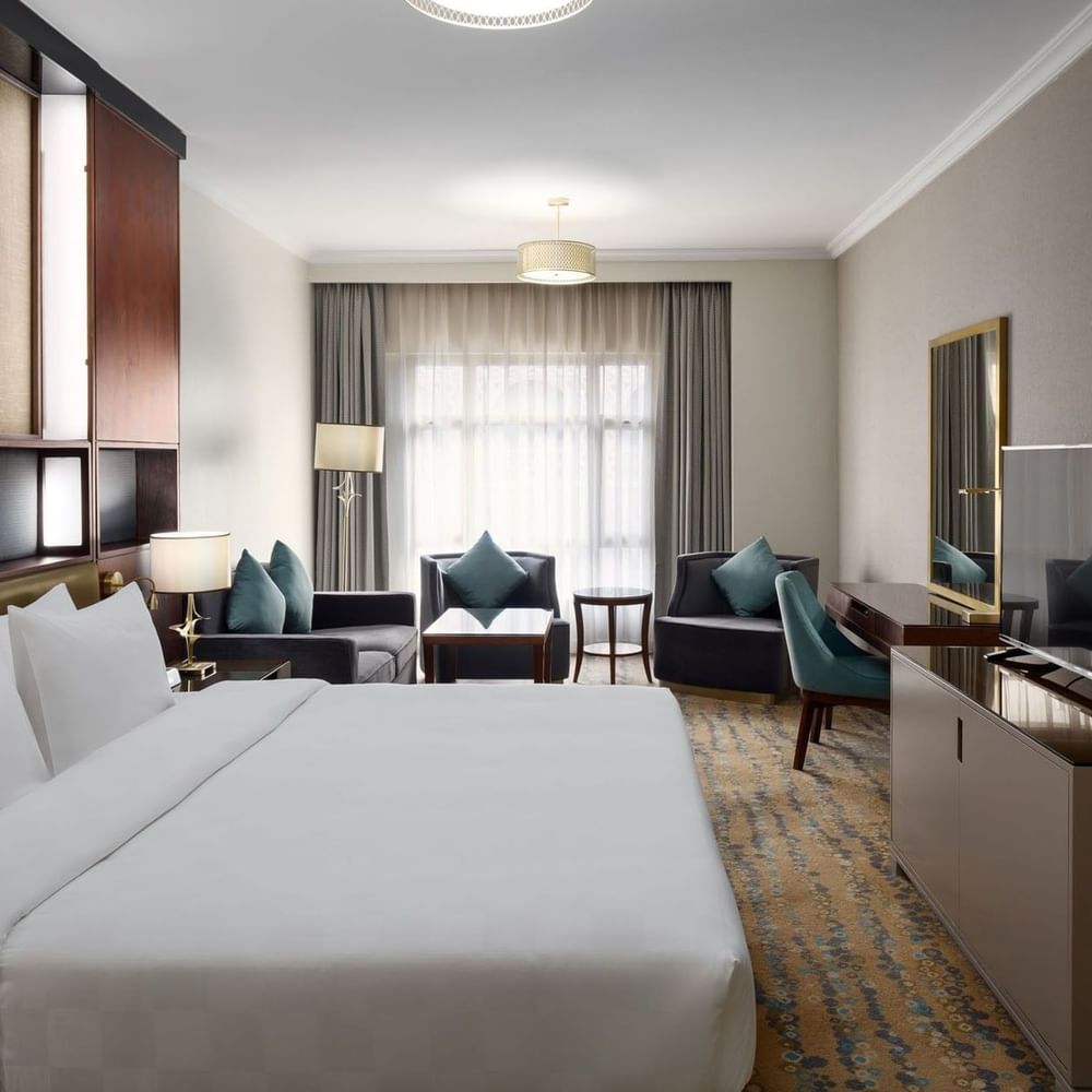 غرفة كينغ تنفيذية في فندق سجى ووريك المدينة، تضم سريرًا كبيرًا، منطقة جلوس أنيقة، مكتب عمل، وتلفاز بشاشة مسطحة بتصميم عصري وإضاءة طبيعية من نافذة واسعة.