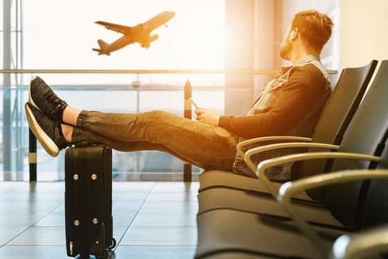 Young man sitting on the chair at airport near Oliver Like Home