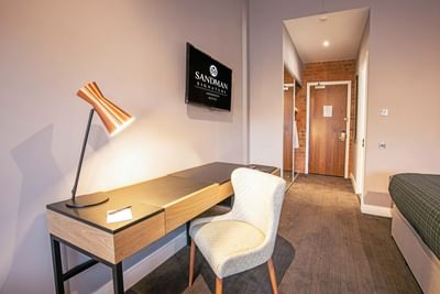 A table with a lamp on top, a chair and a flat-screen tv in a ro