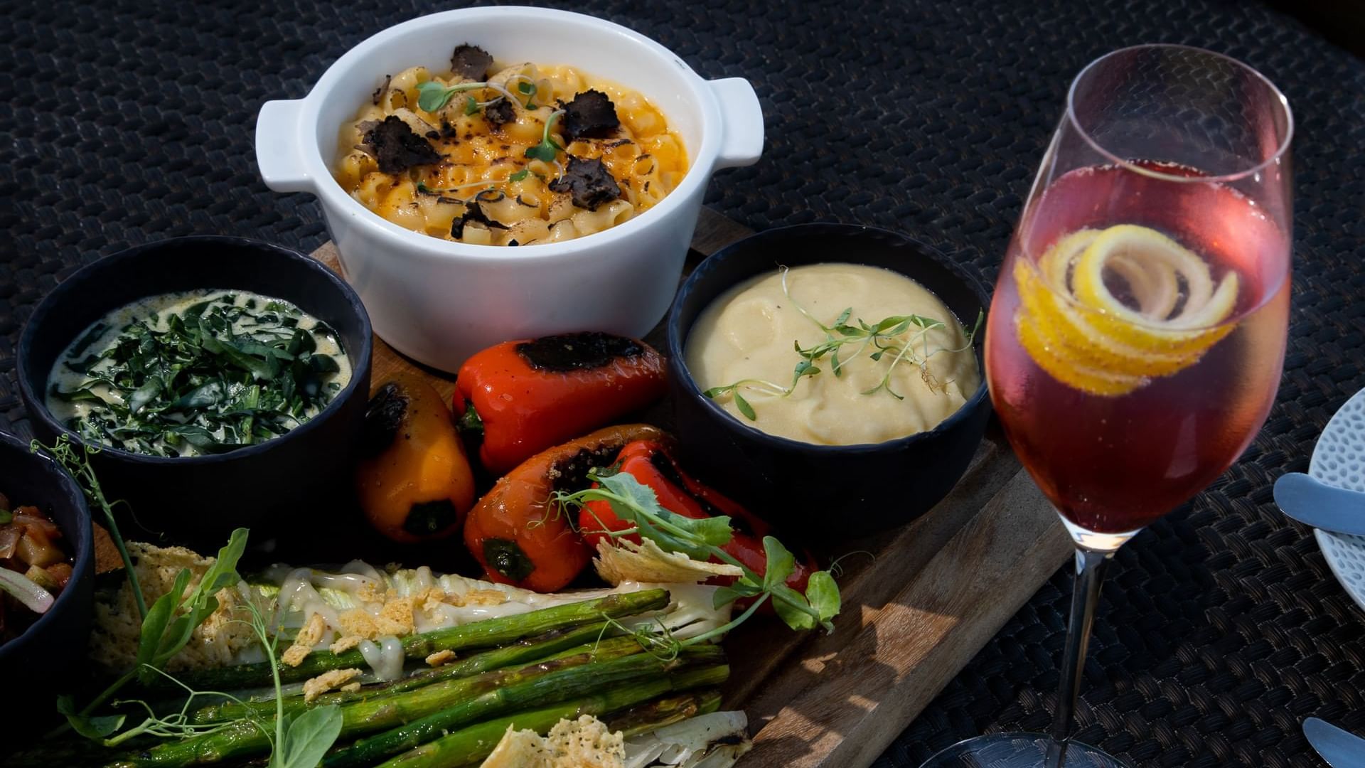 Plato de aperitivos con queso, espárragos y pimientos, acompañado de un coctel en De Cortez Grill House en Hacienda Del Mar Los Cabos.