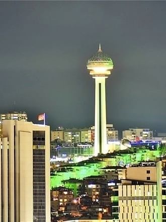 Atakule tower by city buildings under a dark night sky near Warwick Ankara