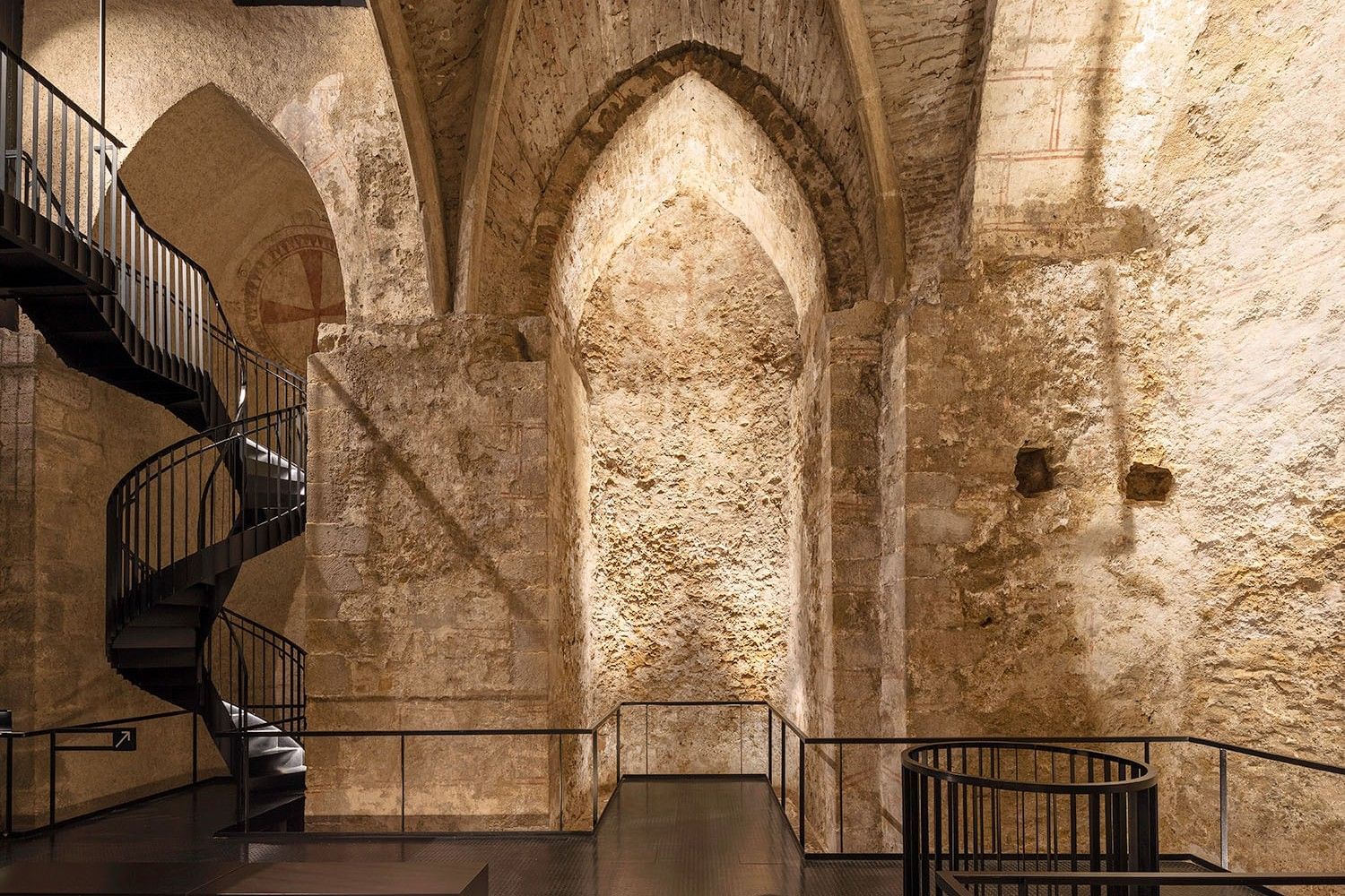 The Virgil Chapel with its medieval vaulted ceilings, exposed stone walls, and the modern black spiral staircase that opens up the historic space