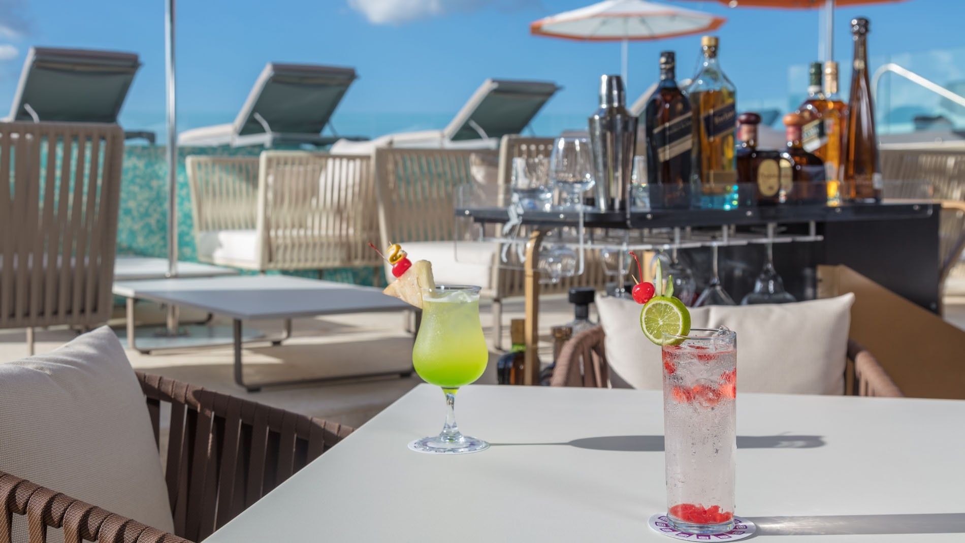 Bright green and red cocktails served in Pool Bar with poolside lounge chairs at Camino Real Merida