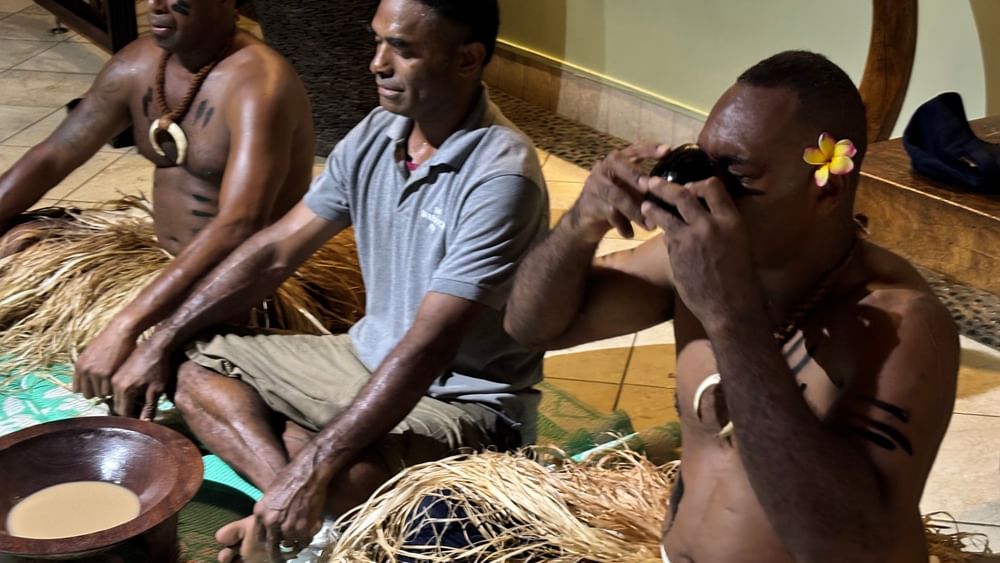 Three men in traditional attire sitting on the floor at Warwick Fiji Resort and Spa.