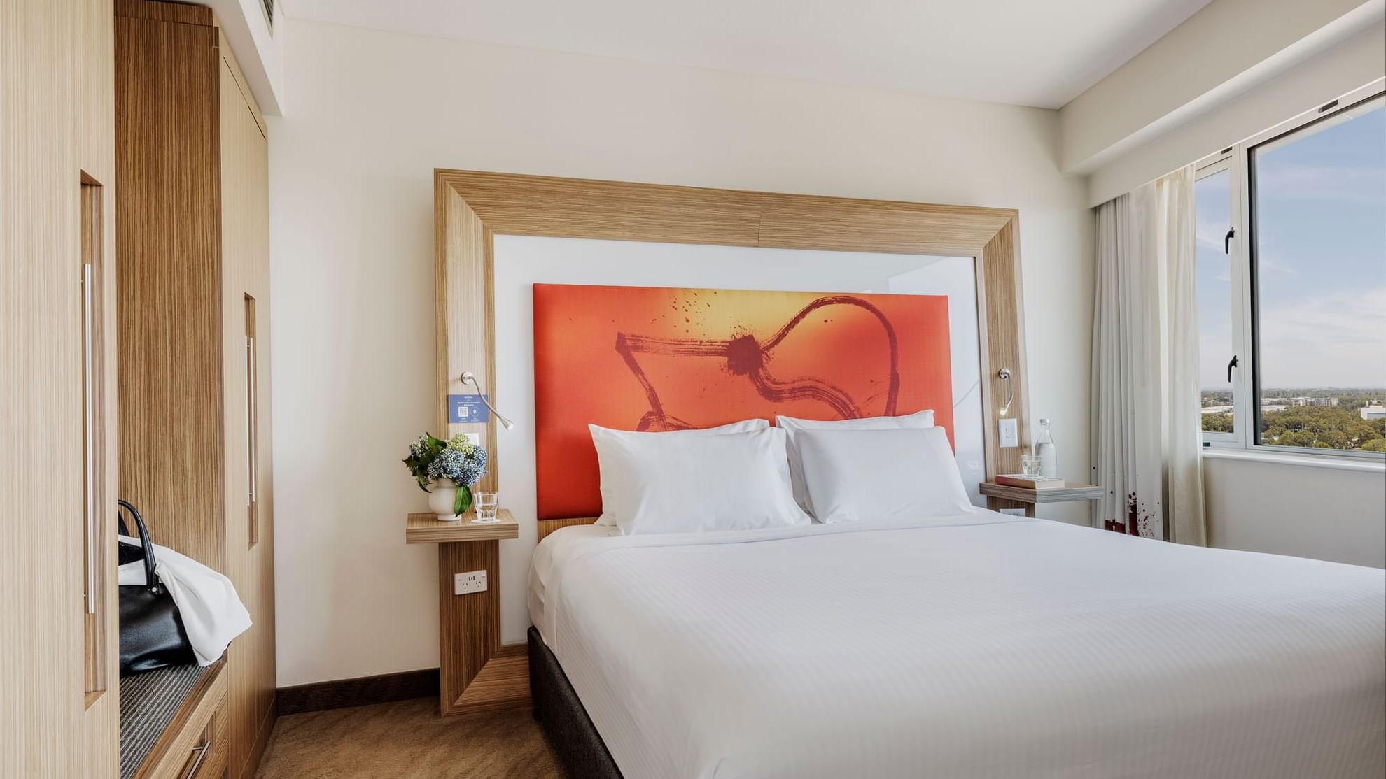 Plush king bed with cushioned headboard and vibrant orange artwork in Superior Spa Suites at Novotel Sydney Olympic Park