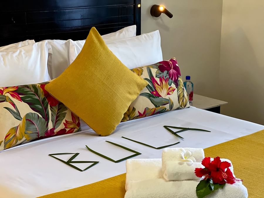 Close-up of a bed with leaves by floral pillows and towels in One Bedroom Villa at TokaToka Resort Nadi Fiji