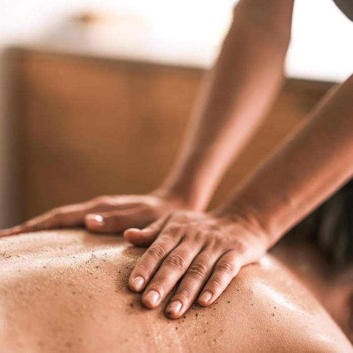 Person massiert den Rücken einer anderen Person während einer Massage-Sitzung.