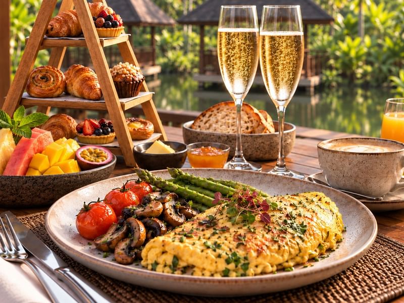 Champagne breakfast on the terrace with omelet, grilled vegetables, pastries, fresh fruit, and orange juice at the banjaran hotsprings retreat, pomelo restaurant