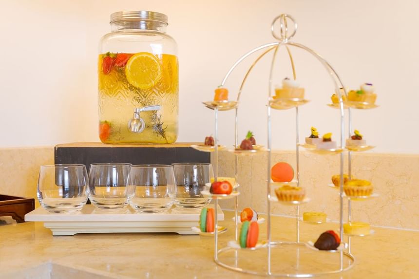 Glass jar of infused fruit water next to an elegant tiered stand filled with colorful desserts at Park Hyatt Saigon