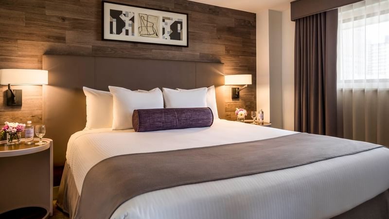 Cozy bed with side tables and wall art in Premiere Suite at Warwick Denver