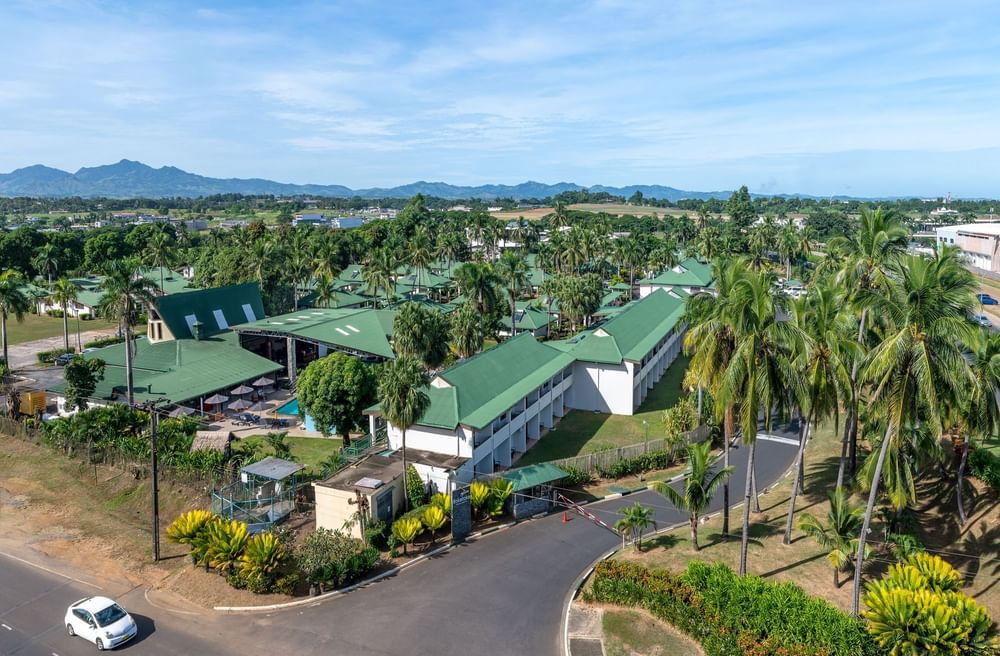Aerial view of a resort with green roofs and a pool surrounding palm trees near TokaToka Resort Nadi Fiji