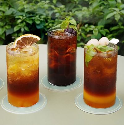 Delightful selection of four iced coffee and tea drinks with various fruit garnishes outdoors at Hanoi Daewoo Hotel