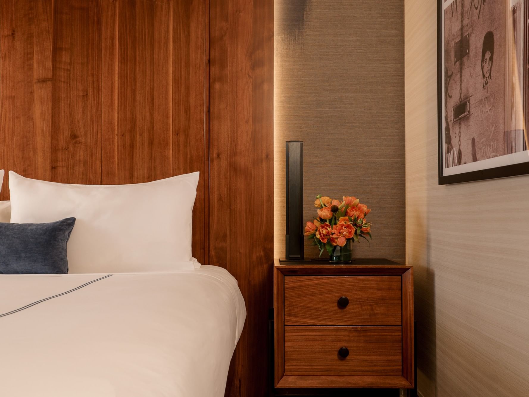 Elegant Grand Deluxe Room with wooden furniture and vibrant flower arrangement at Gansevoort Meatpacking NYC.
