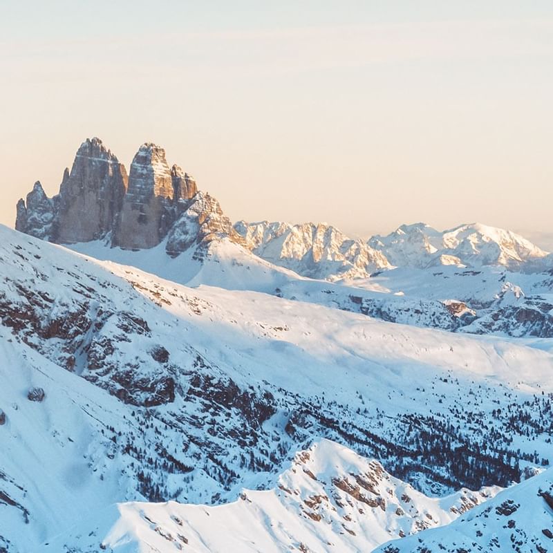 Panorama eines schneebedeckten Gebirges mit hohen Gipfeln und wolkenlosem Himmel im Hintergrund.